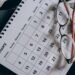 Óculos de leitura apoiados sobre um calendário mensal impresso
